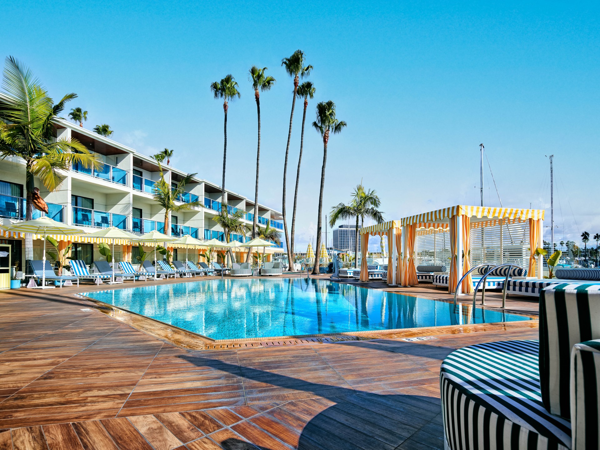 a pool with chairs and a building with palm trees