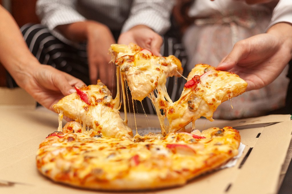 a group of people holding slices of pizza