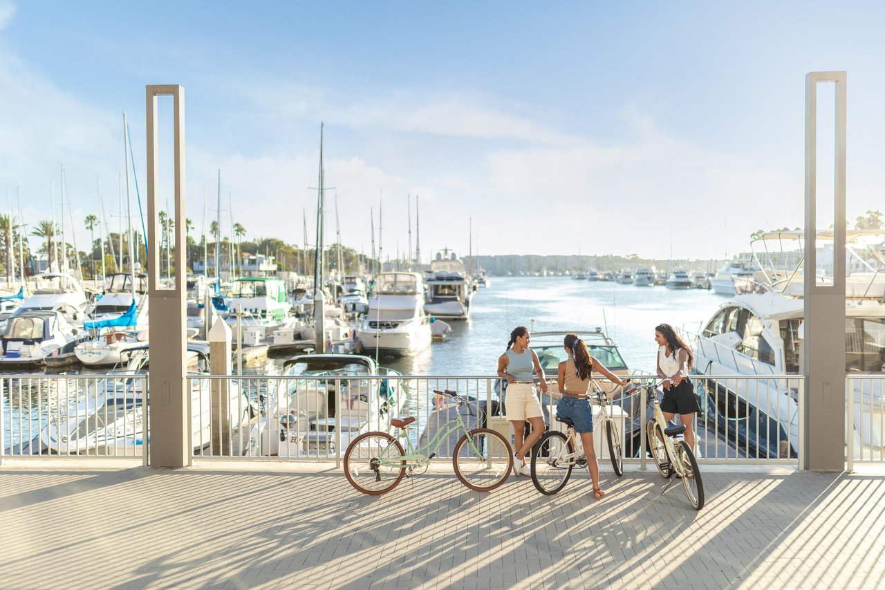 a group of women standing on a dock with bikes and boats in the background