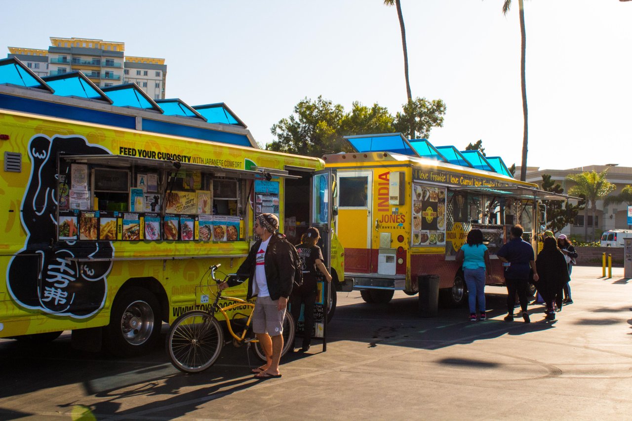 a group of people standing next to food trucks