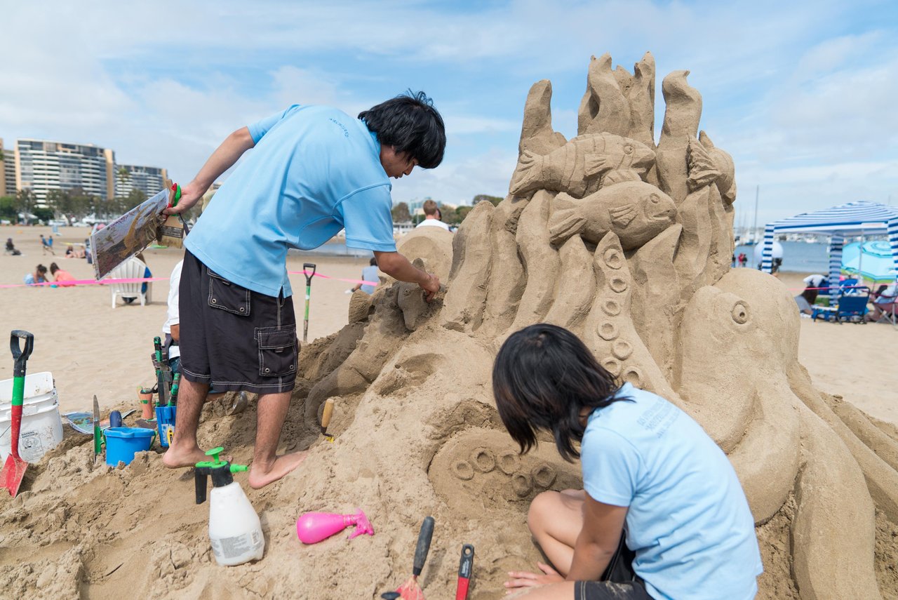 a group of people building sand sculpture on a beach