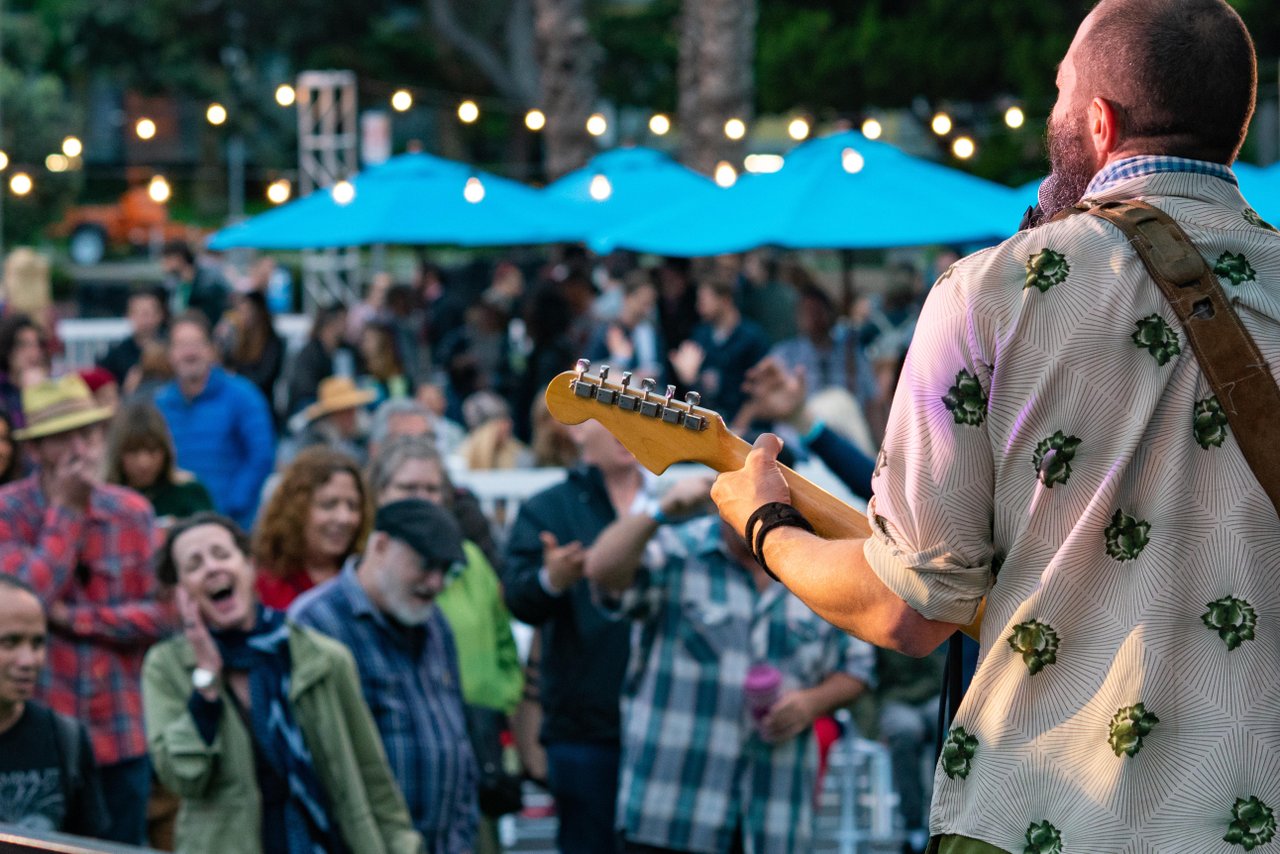 a man playing guitar in front of a crowd of people