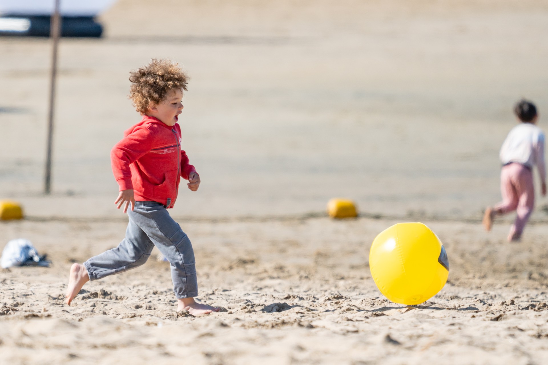 a child running on sand with a yellow ball