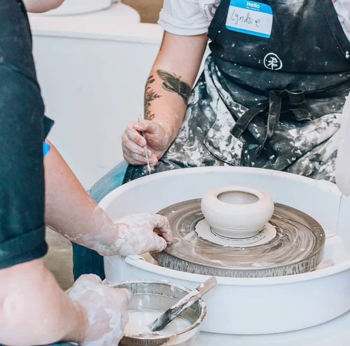 a person painting a bowl on a pottery wheel