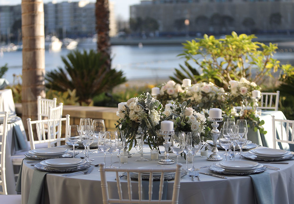 a set table with white tables and white flowers