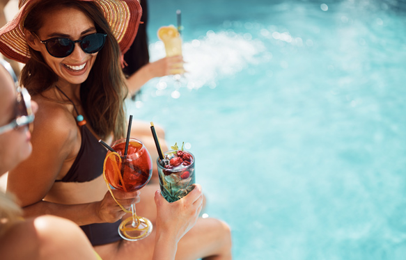 a woman holding drinks by a pool
