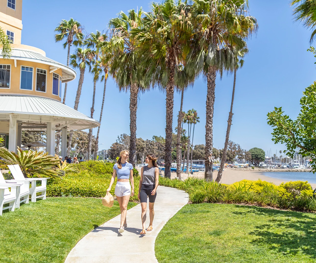 two women walking on a sidewalk by a beach