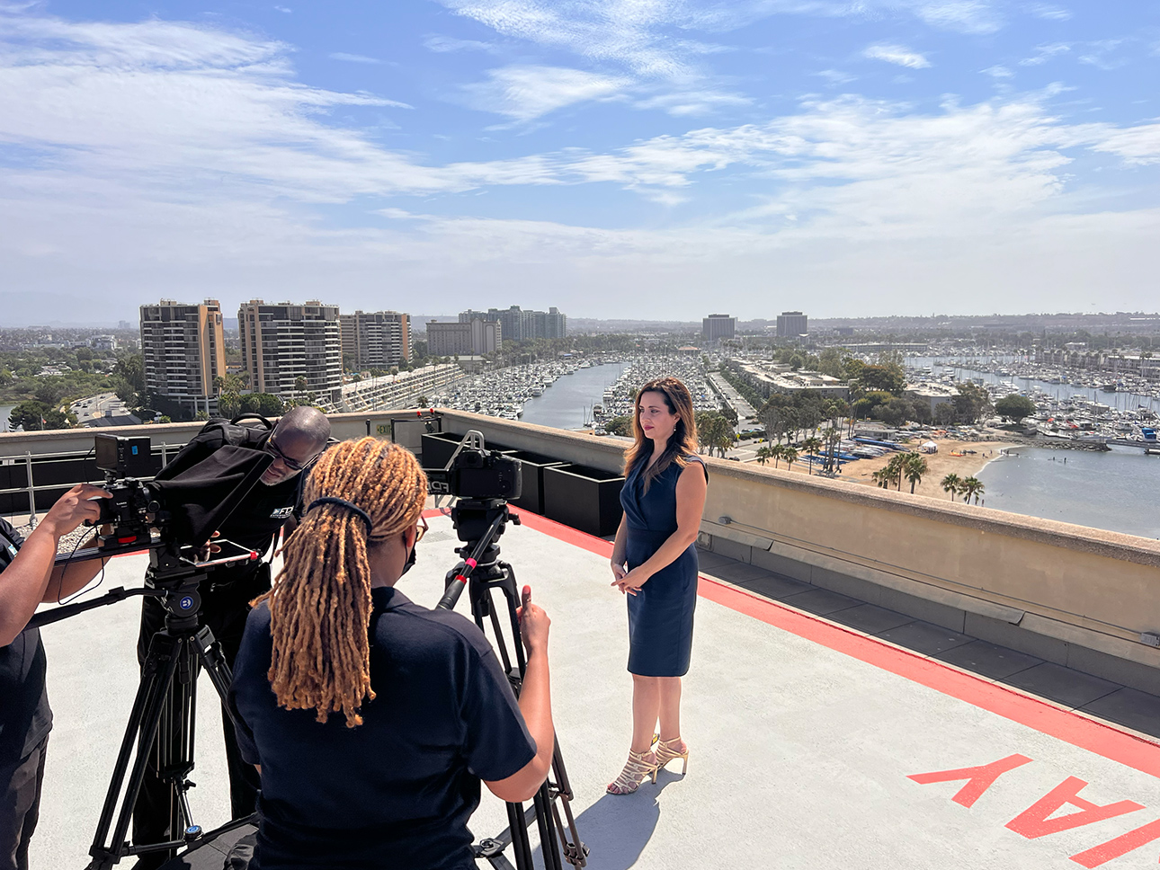 a woman standing on a roof with camera equipment and a woman on a tripod
