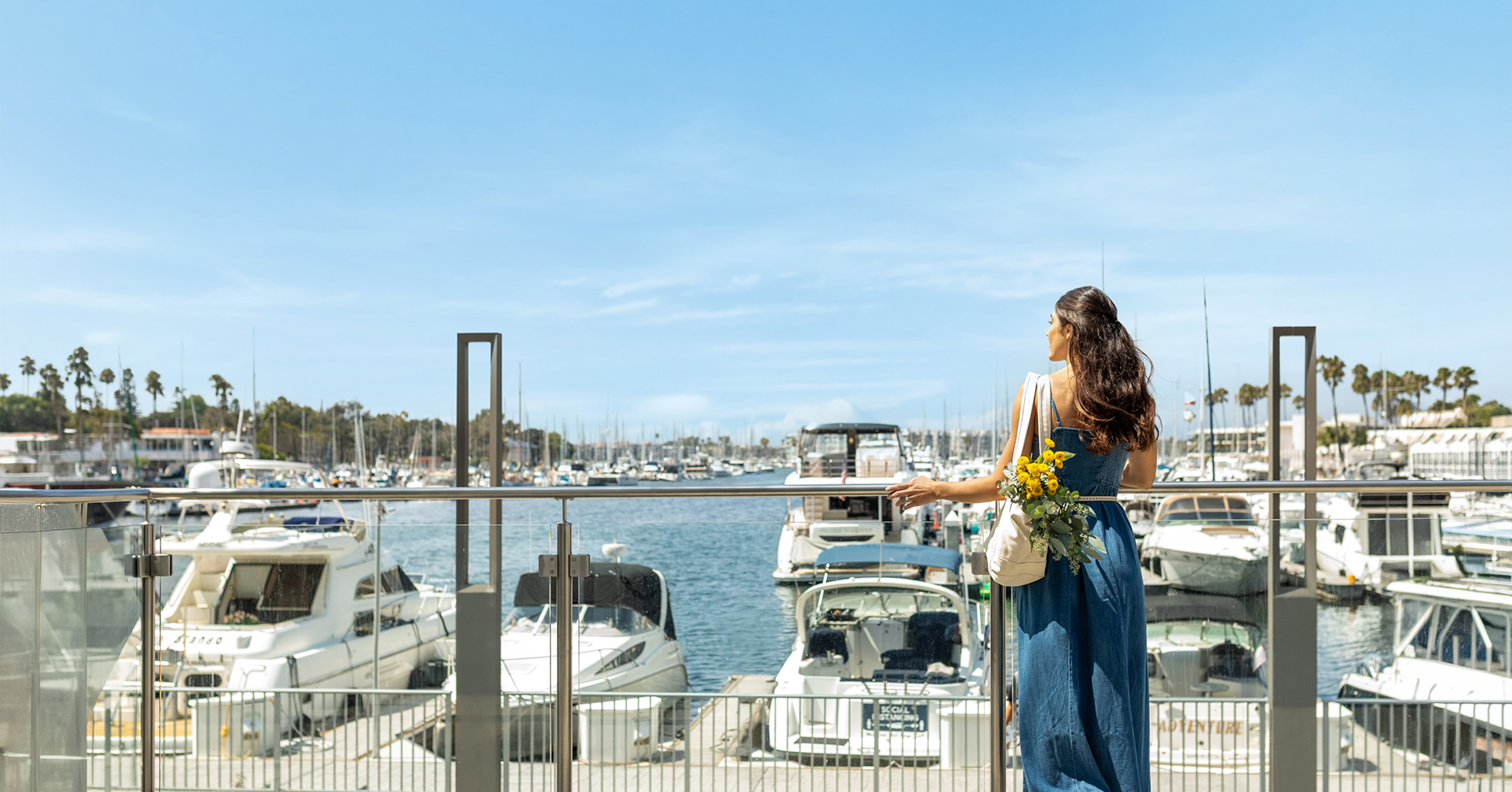 a woman in a blue dress looking at boats in the water