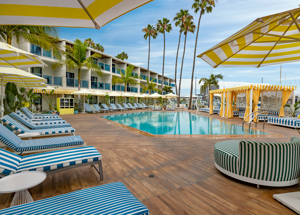 a pool with chairs and umbrellas in front of a hotel