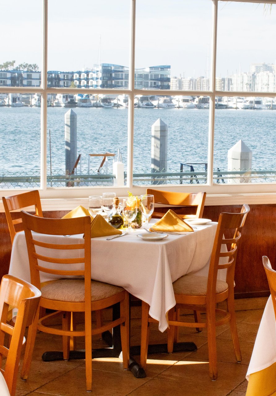 a table with a white tablecloth and chairs with a view of water and city