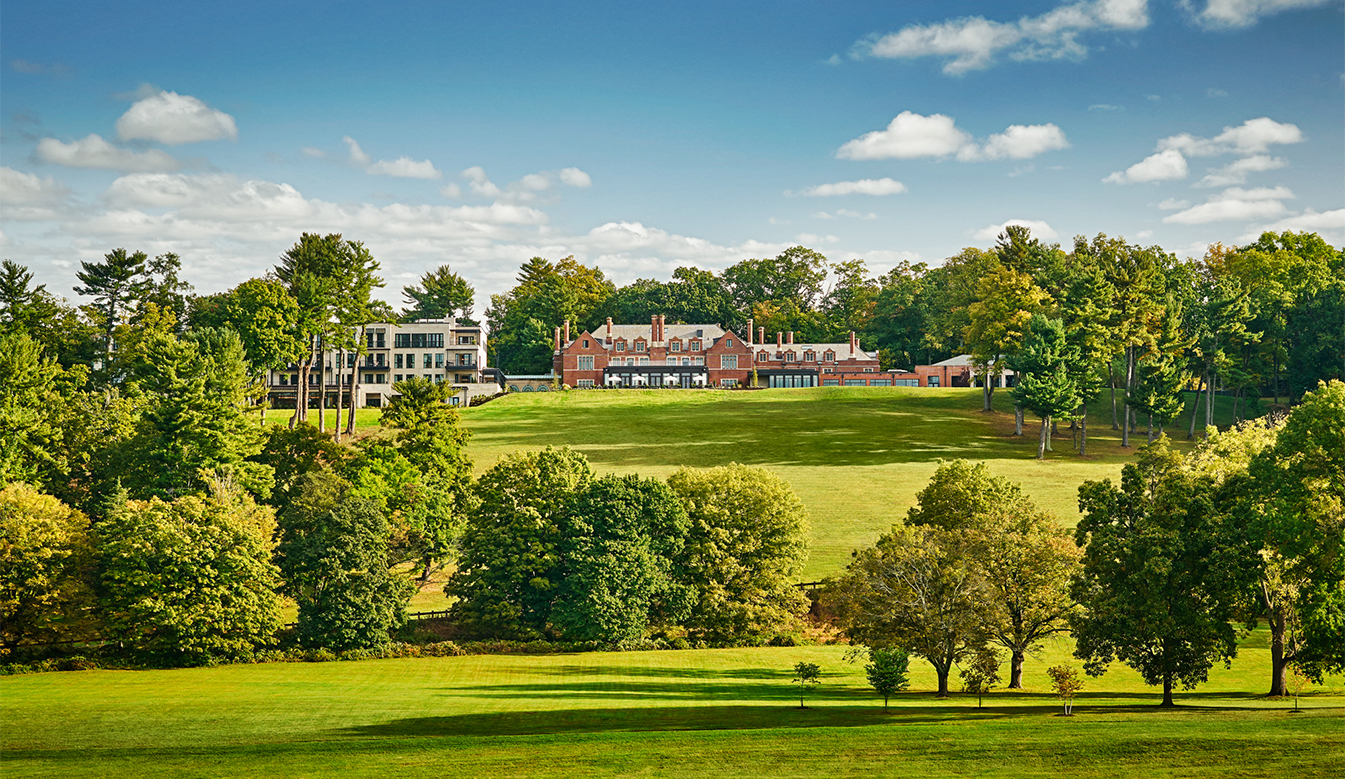 a large green field with trees and a building in the background