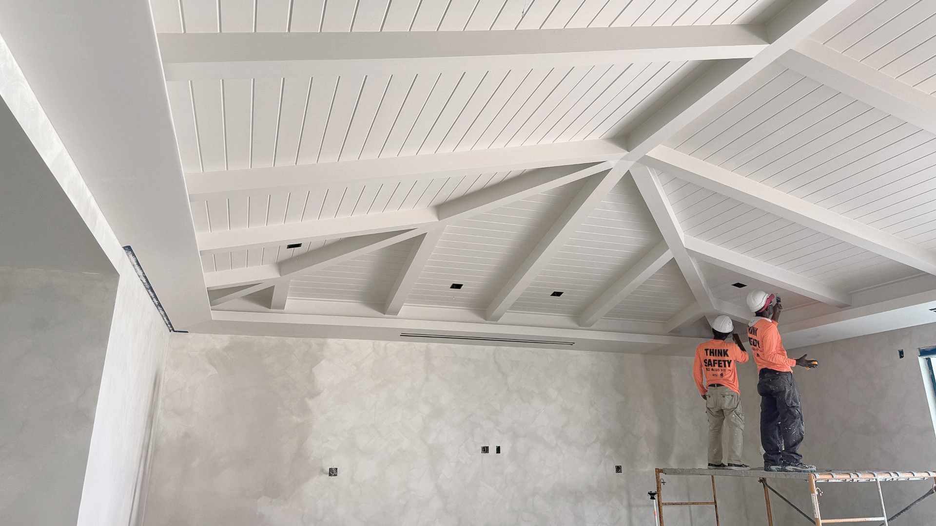 a man standing on a scaffolding in a room with white ceiling