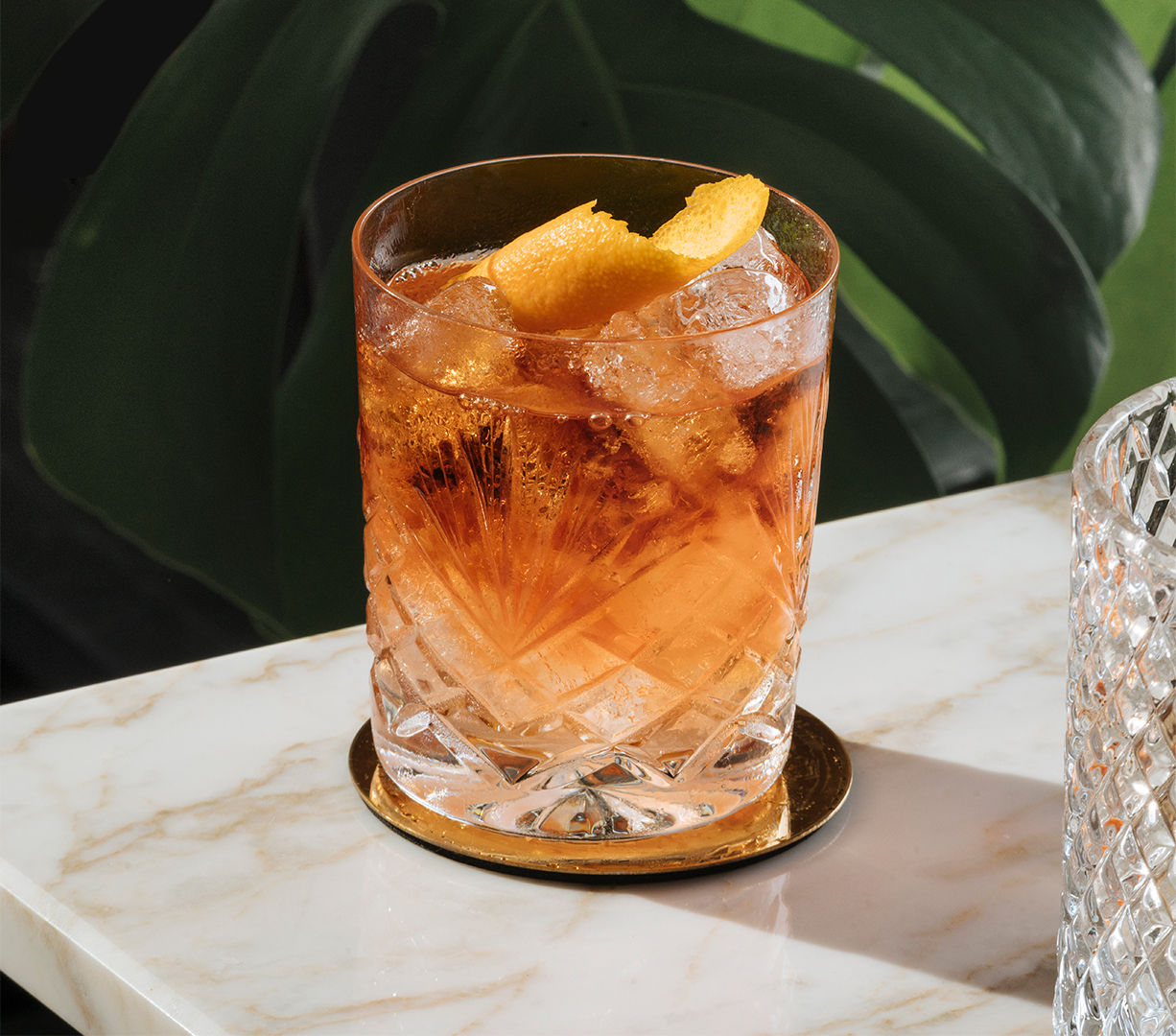a glass of ice tea with orange slices on a marble surface