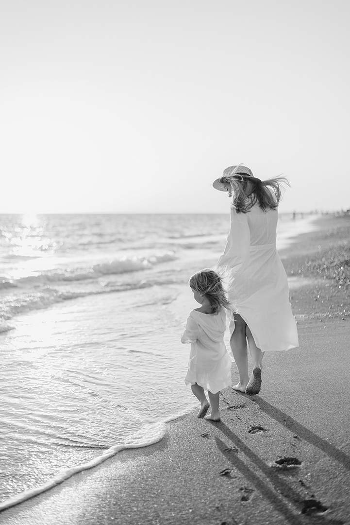a woman and a child walking on a beach