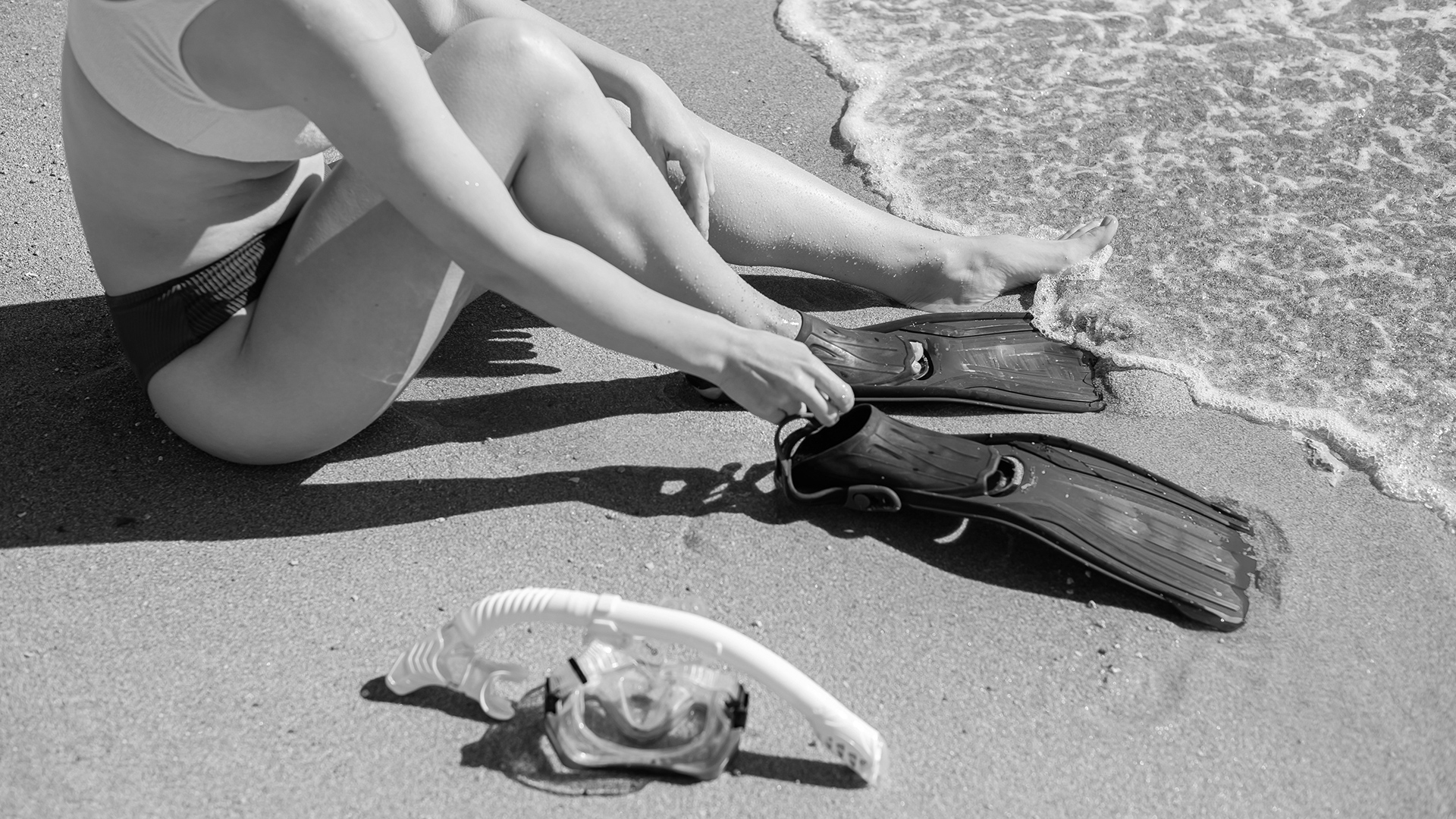a person sitting on the beach with snorkeling gear