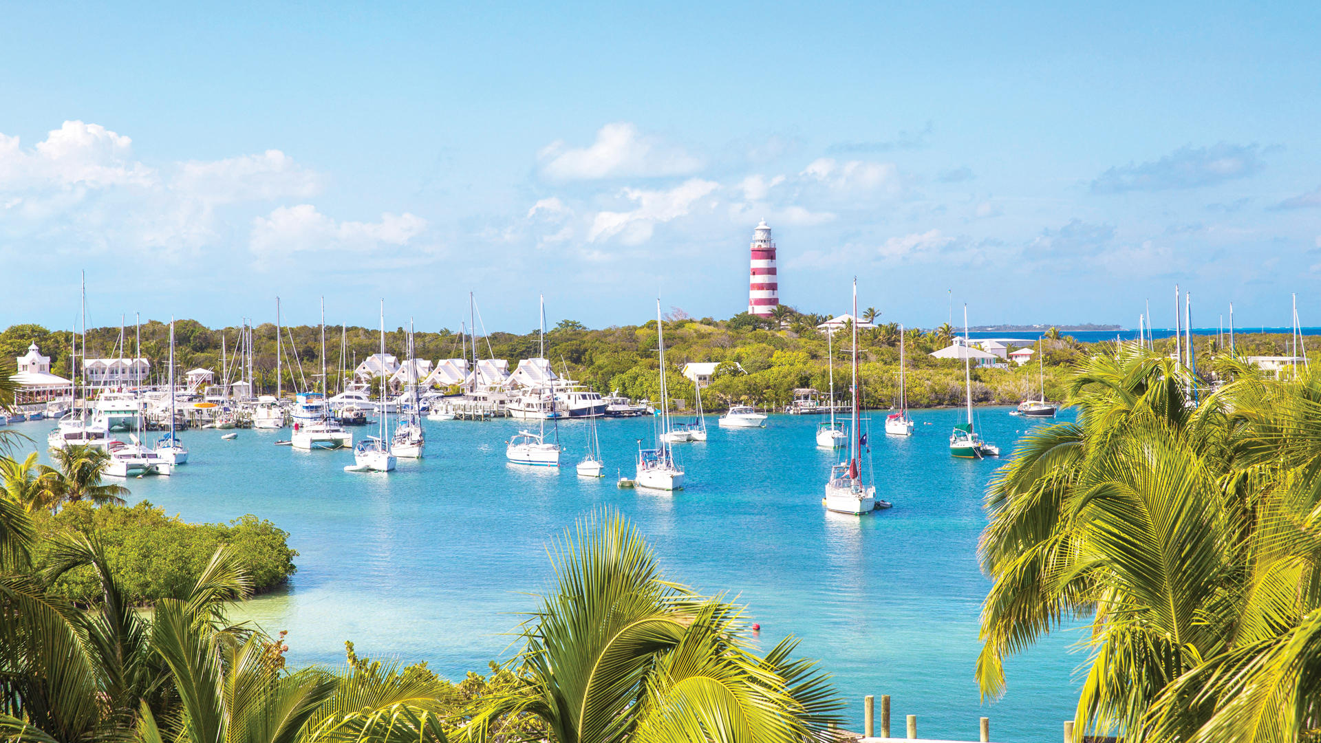 a group of boats in a bay with a lighthouse in the background
