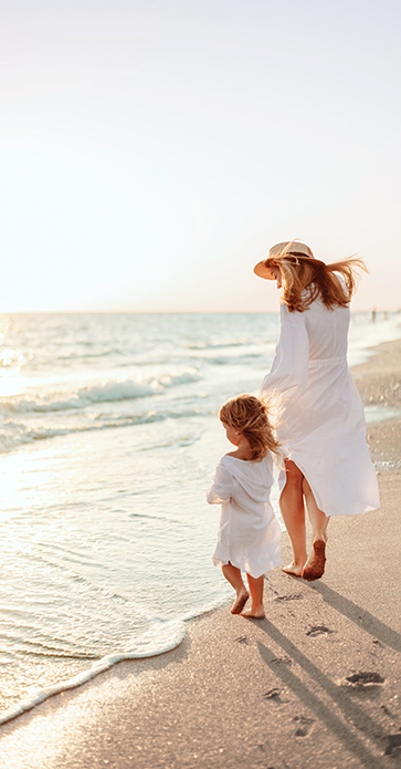 a woman and child walking on a beach