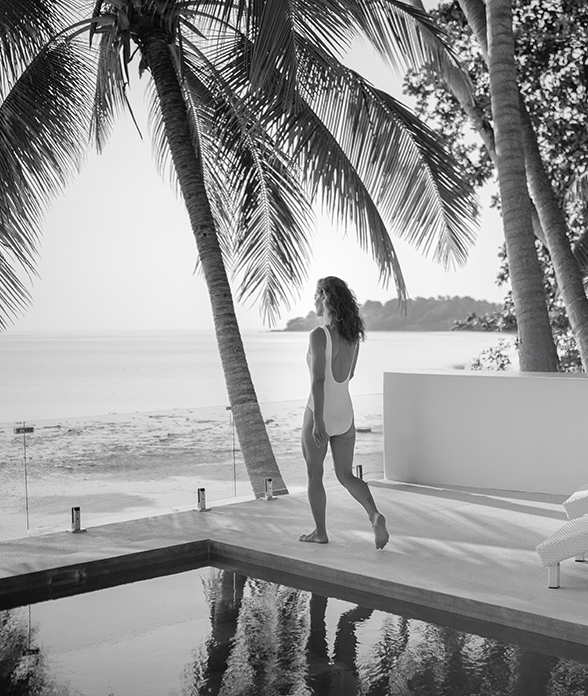 a woman in a swimsuit walking by a pool