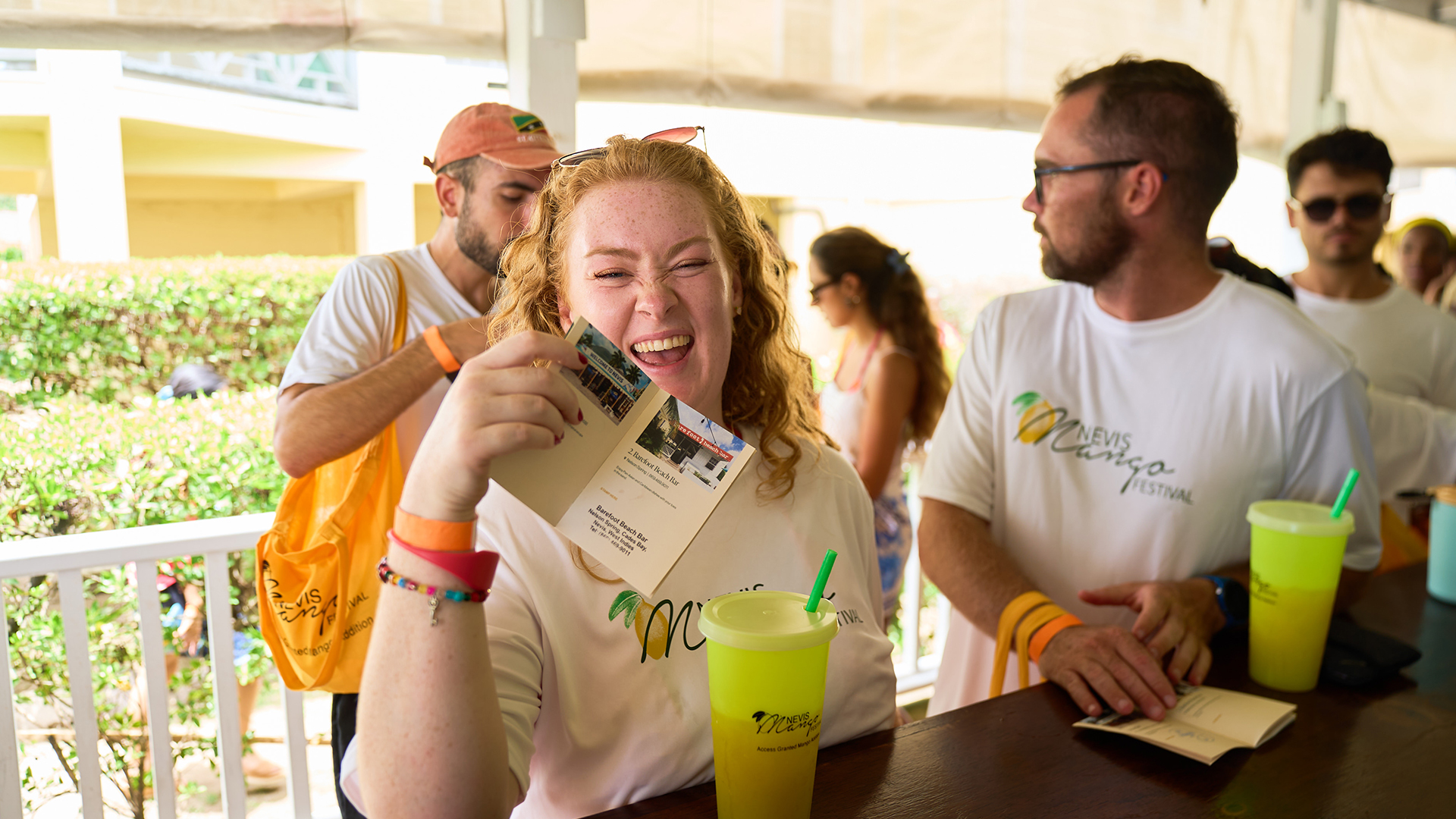 a woman laughing at a table with a drink and a card