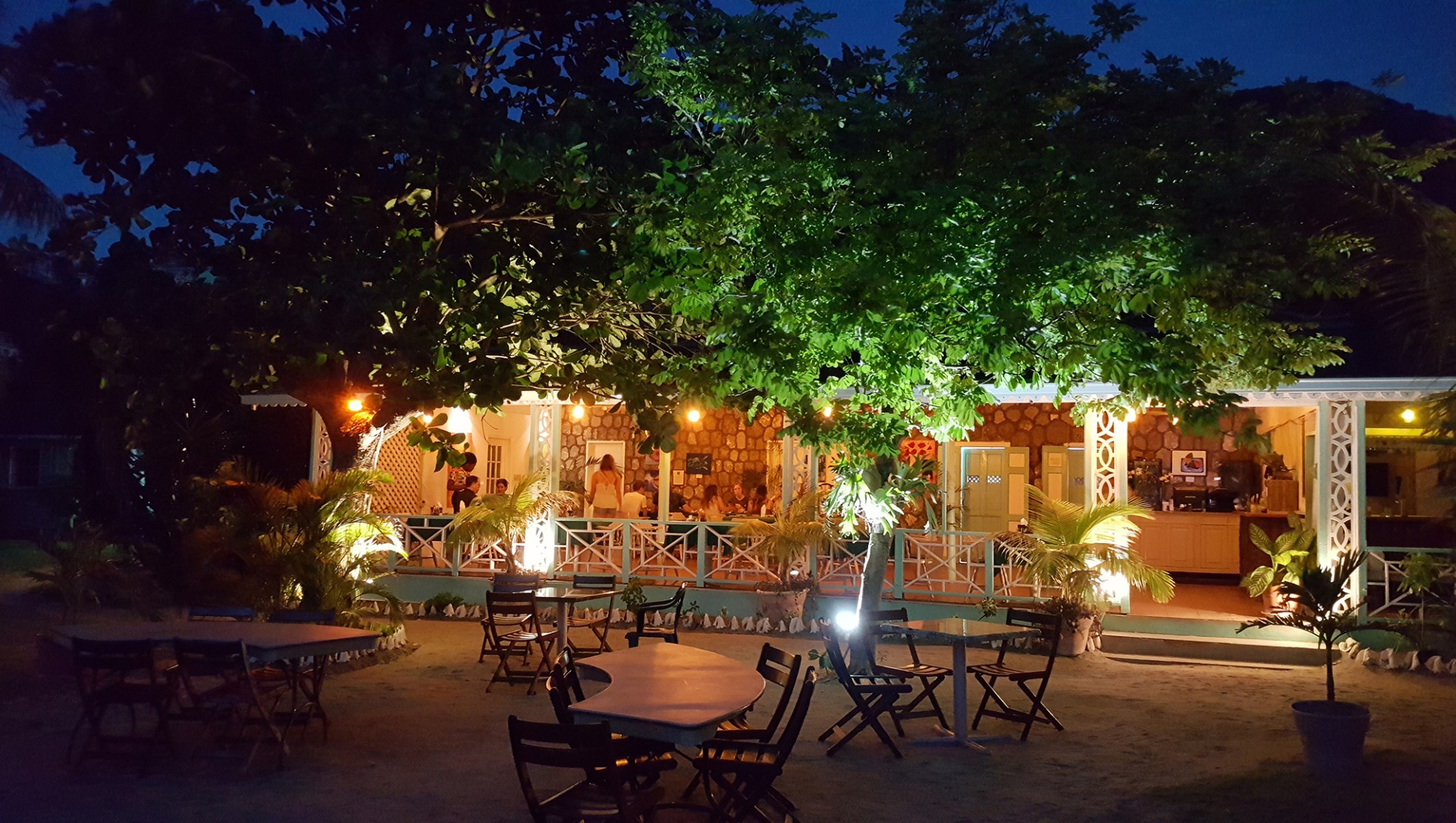 a group of tables and chairs under trees at night