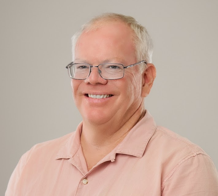 a man wearing glasses and a pink shirt