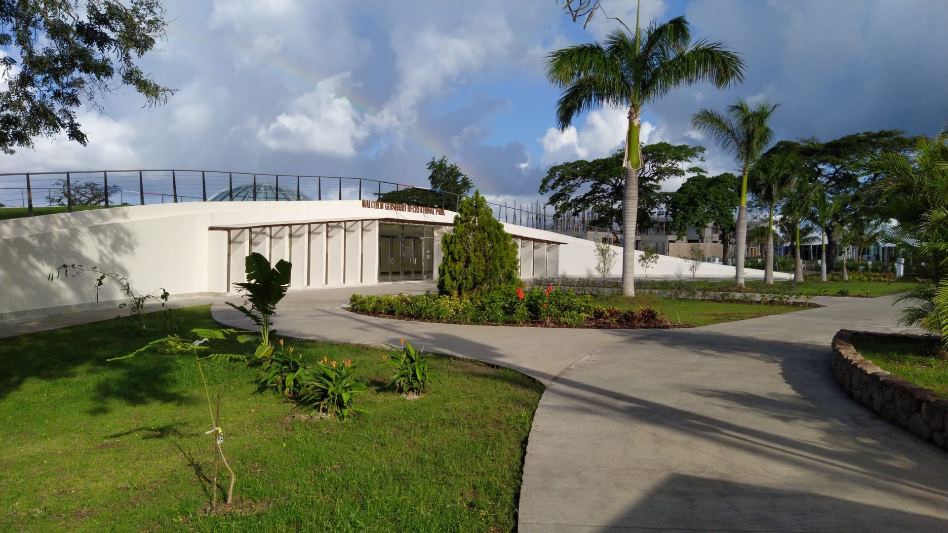 a building with a walkway and a rainbow in the sky