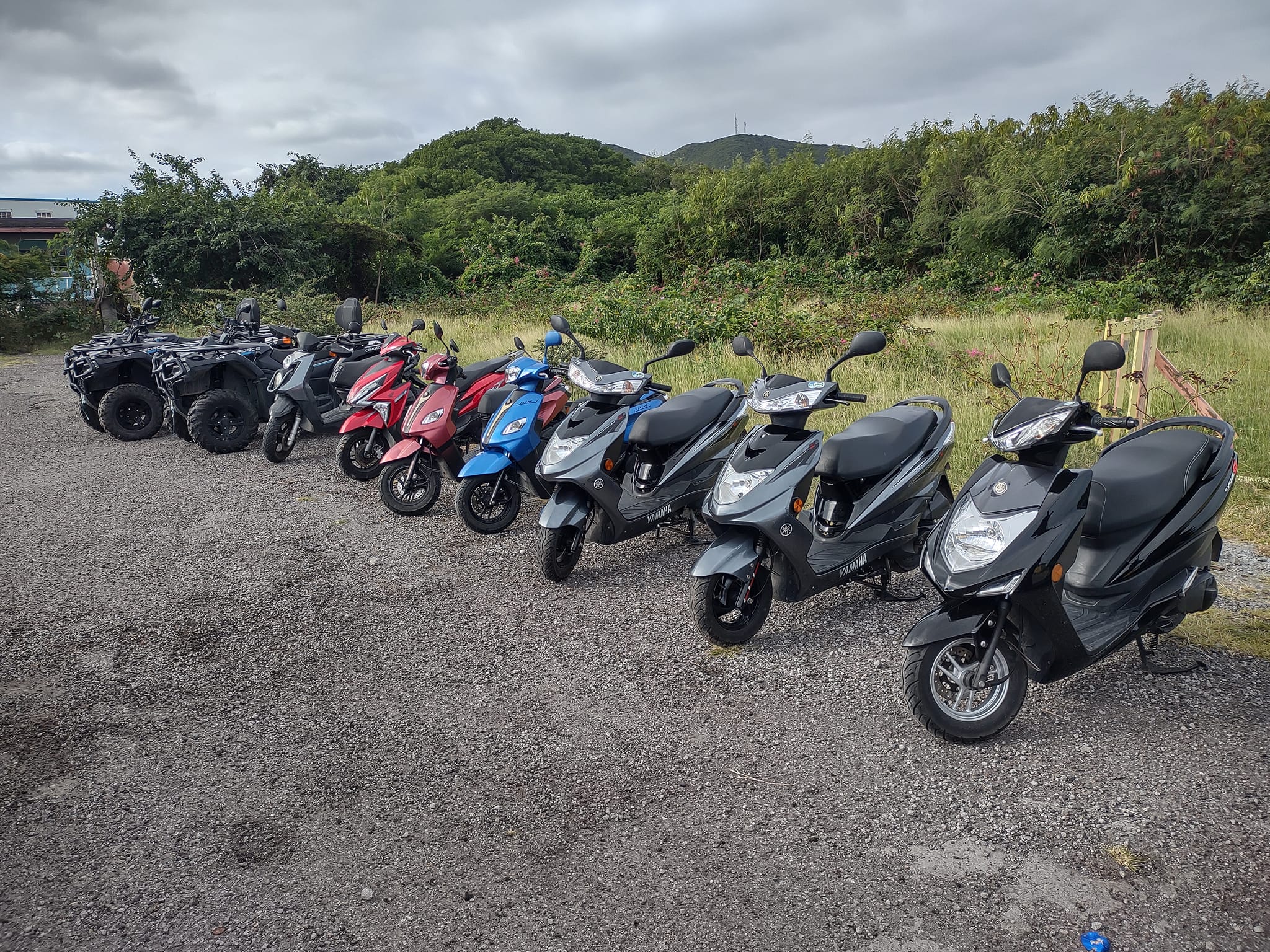 a row of scooters parked on gravel