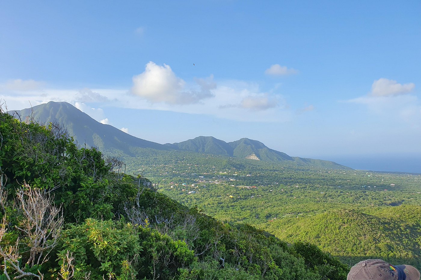 a landscape of a green valley with mountains and blue sky