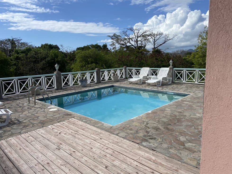 a pool with a deck and a deck with trees in the background