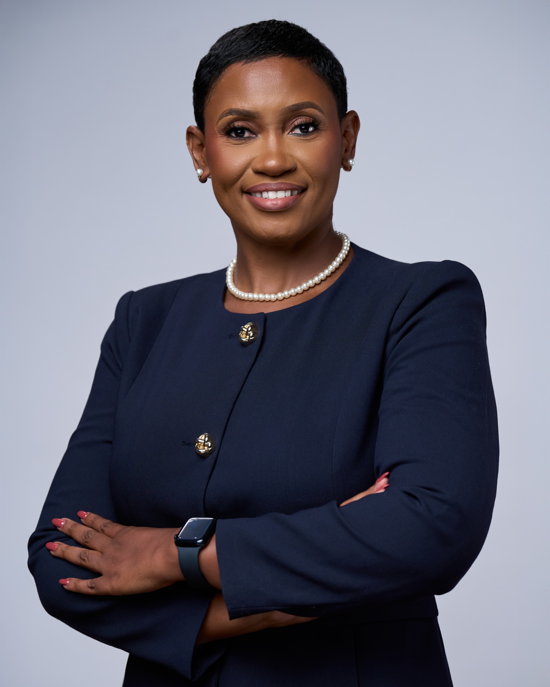 a woman with short hair wearing a pearl necklace and a blue jacket