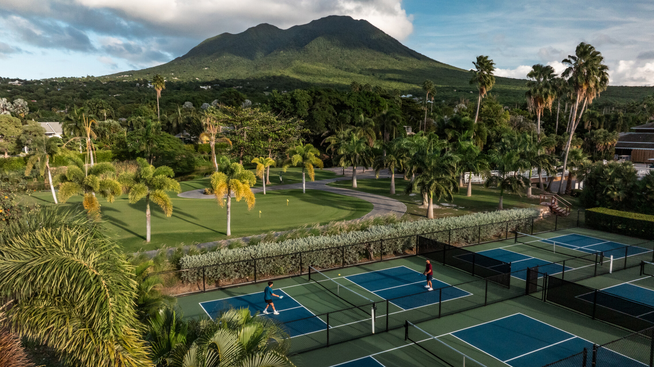 a tennis court with trees and mountains in the background
