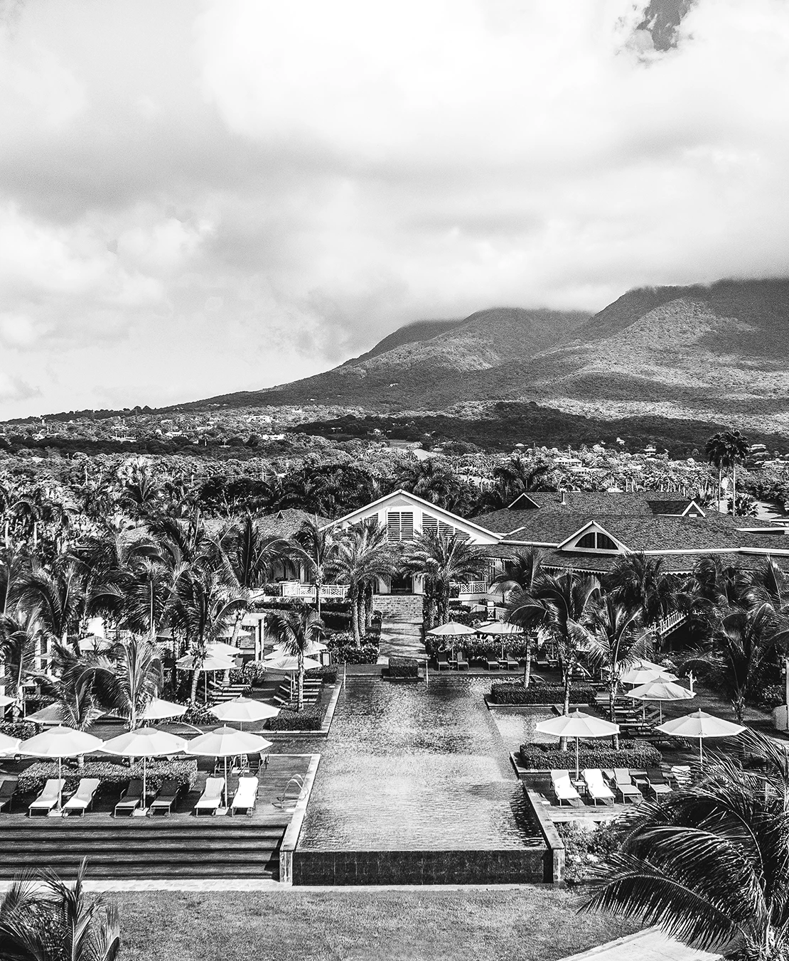 a pool with umbrellas and chairs in front of a large building
