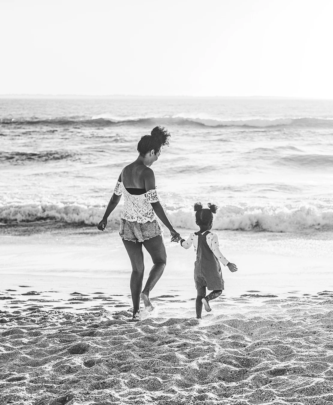 a woman and a child walking on a beach