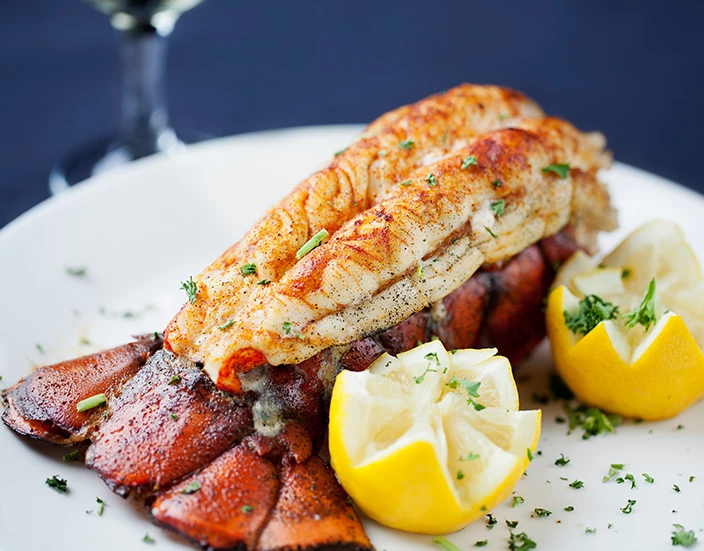 a lobster tail with lemons and parsley on a white plate