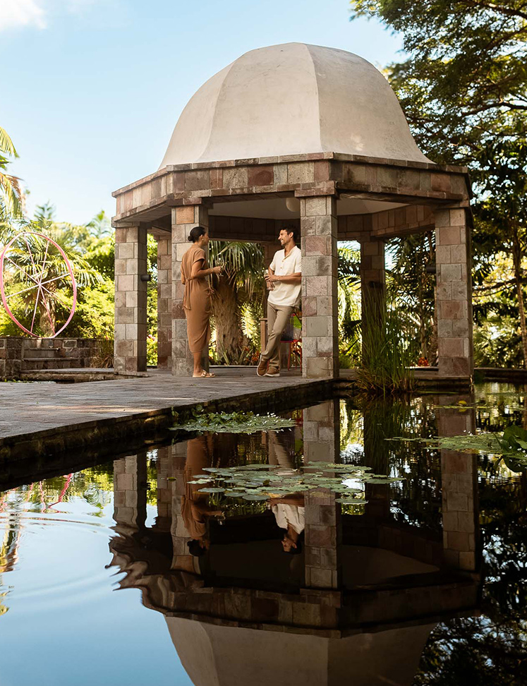 a man and woman standing in a gazebo next to a pond