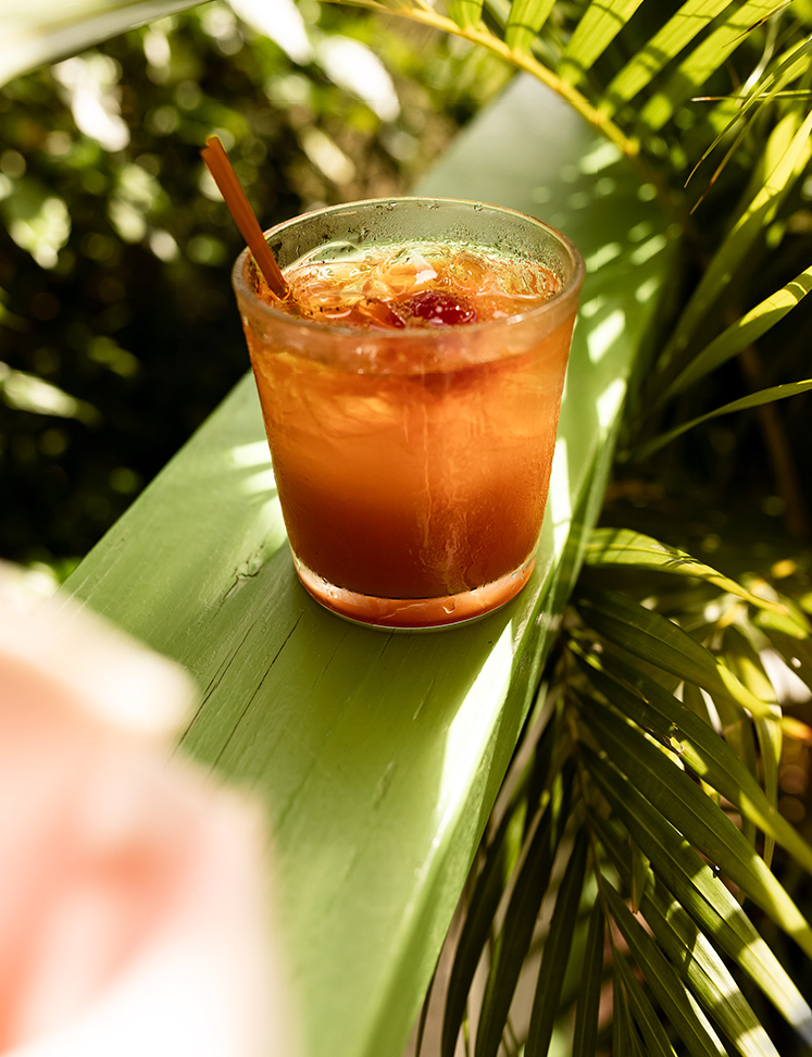 a glass of drink on a green railing