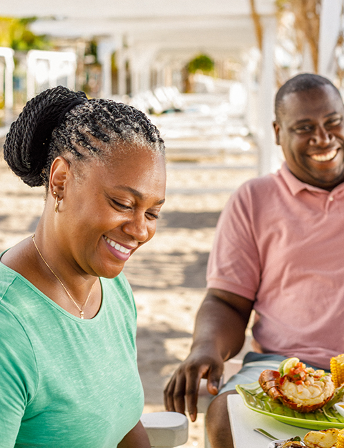 a man and woman smiling at a table with food
