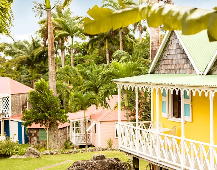 a yellow house with a white railing and a green roof