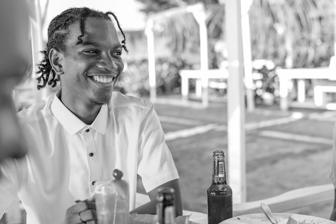 a man smiling at a table with bottles of beer
