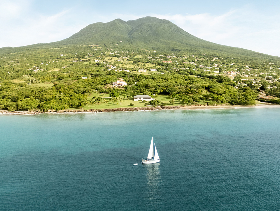 a sailboat in the water with a mountain in the background