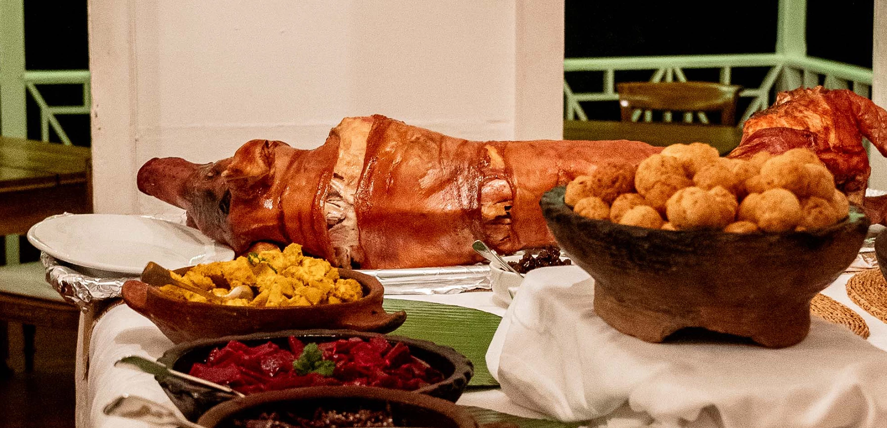 a pig sitting on a table with food in bowls