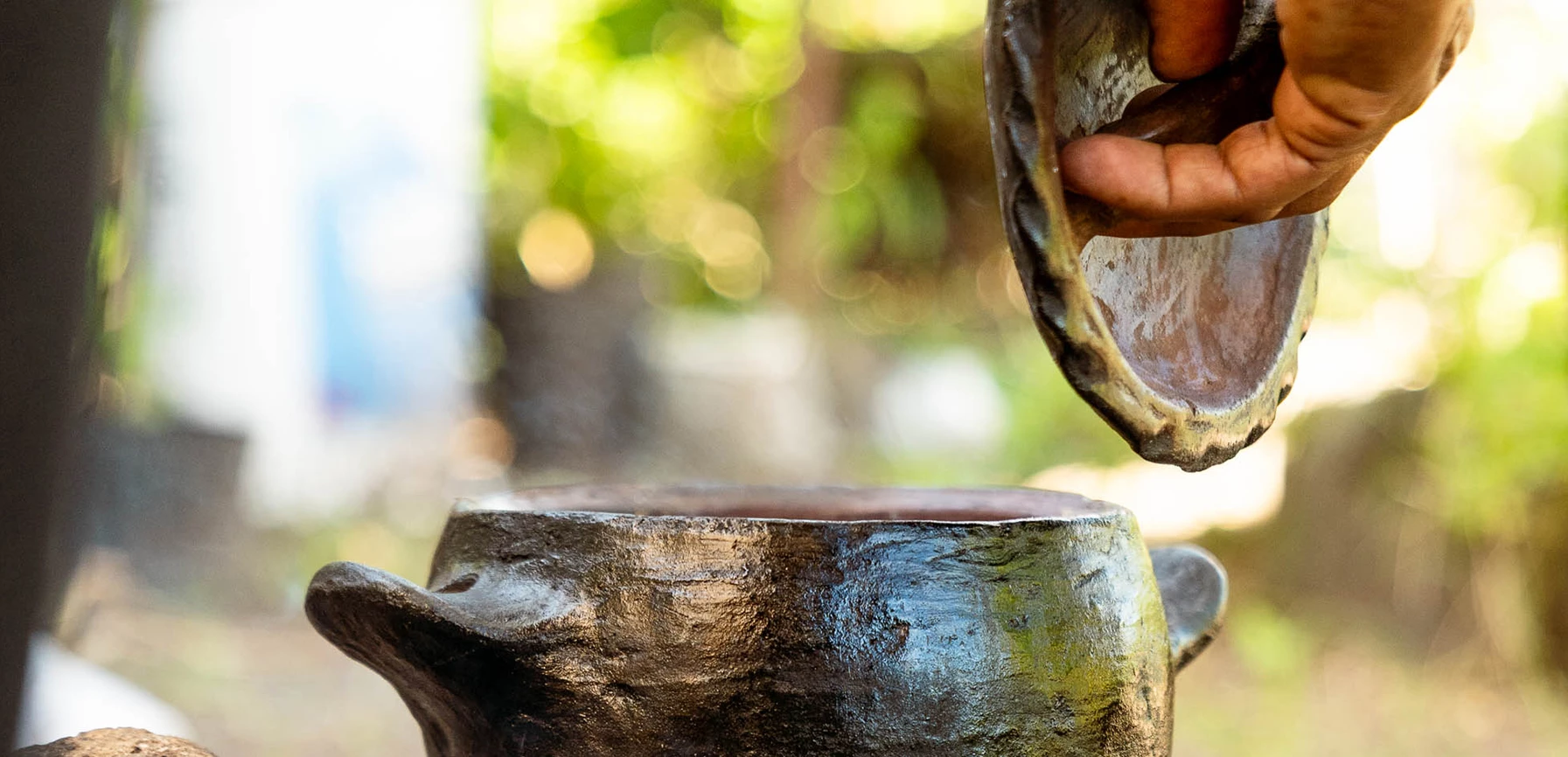 a hand pouring a clay pot