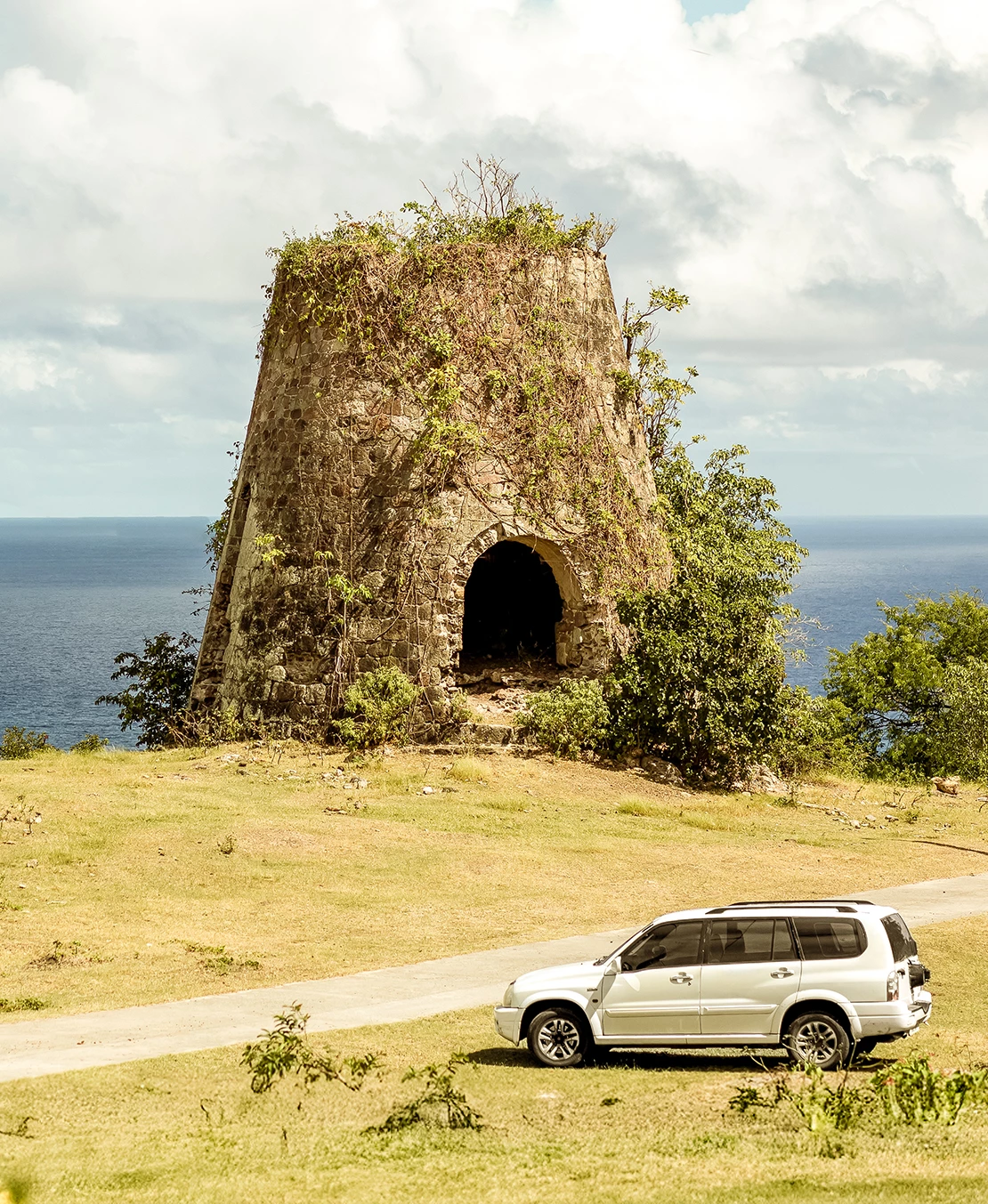 a car parked on a road next to a stone structure with a large body of water