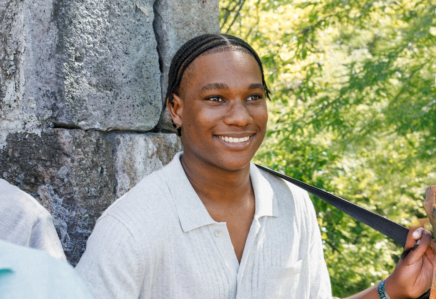 a man smiling with a strap around his shoulder