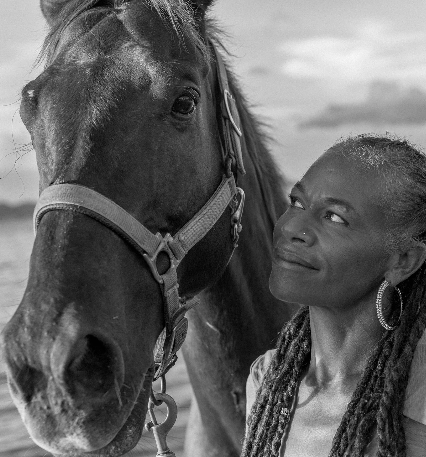 a woman with braids looking at a horse