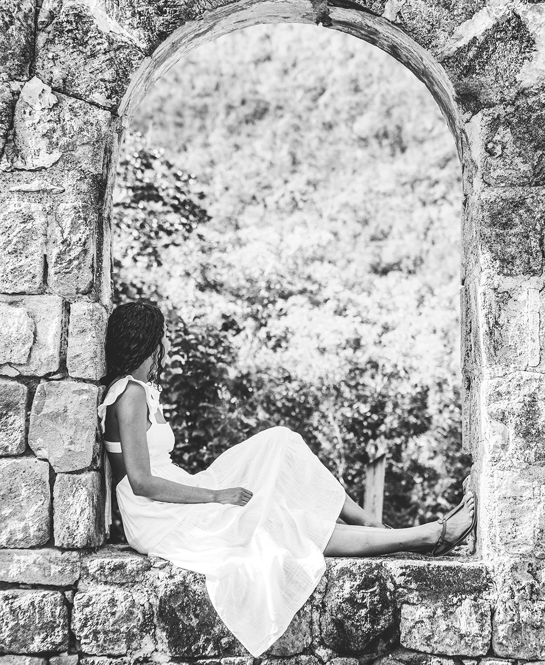 a woman sitting in a stone arch
