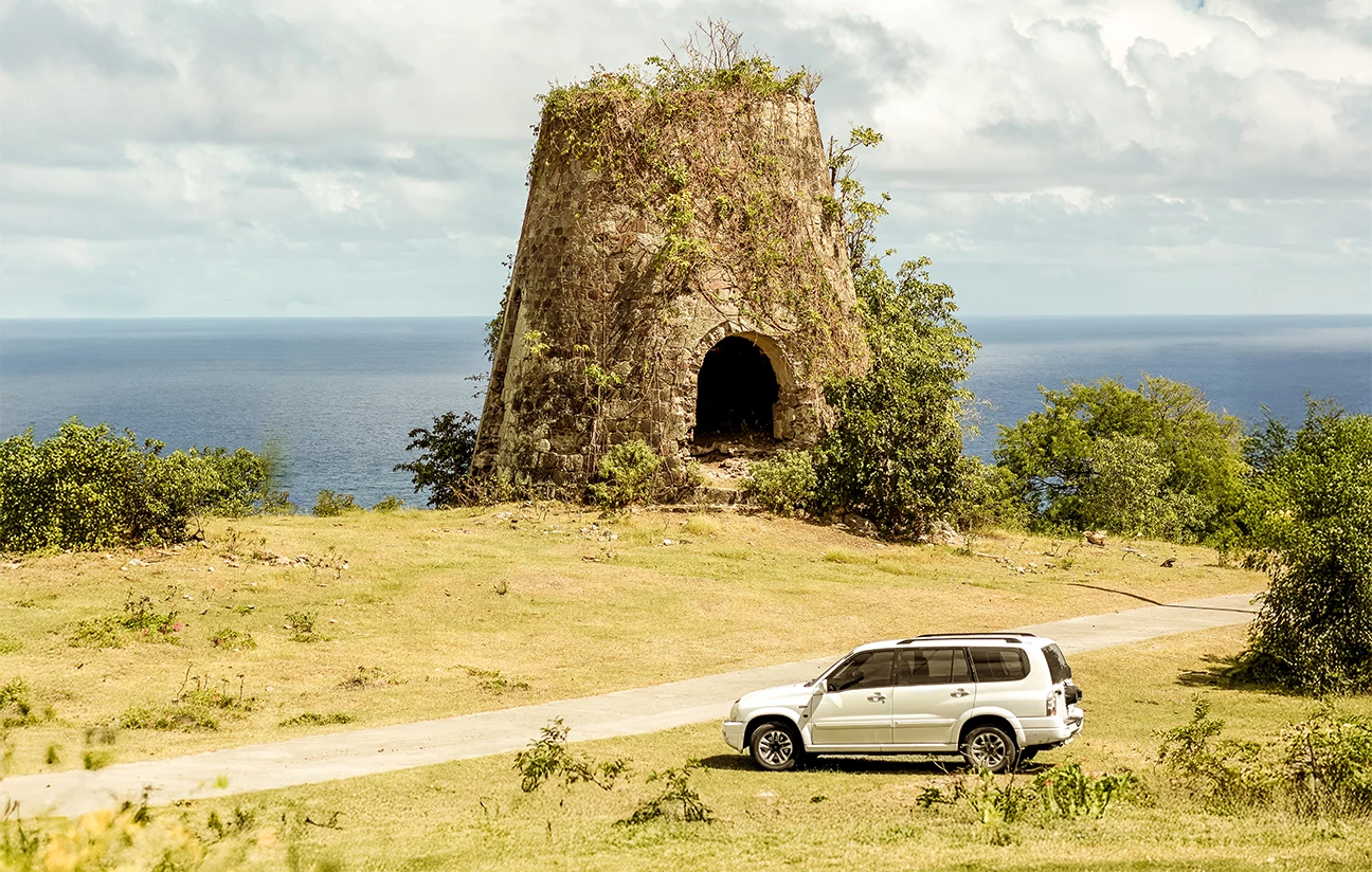 a car parked on a road next to a stone structure