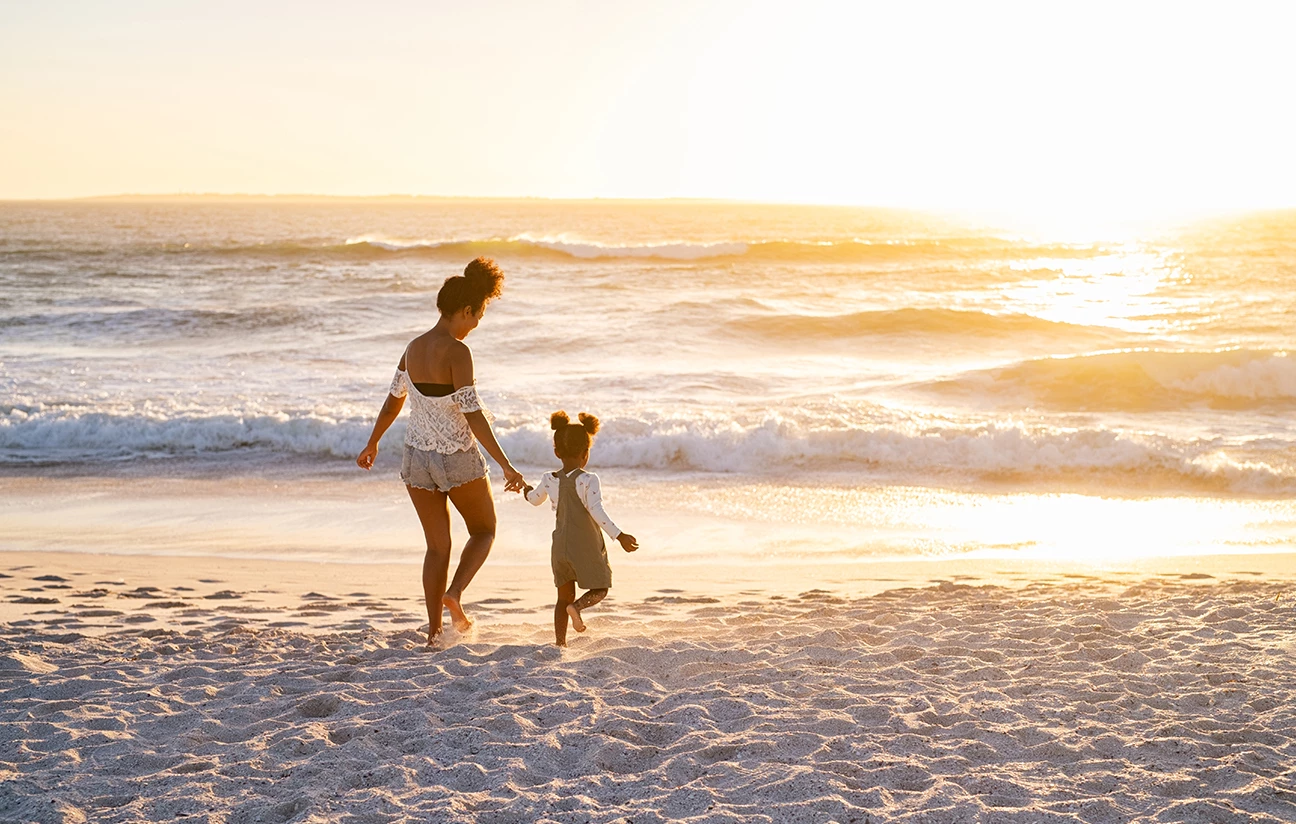 a woman and a child walking on a beach