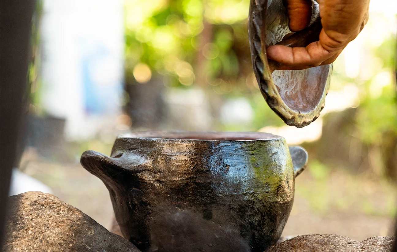 a hand pouring a pot into a pot